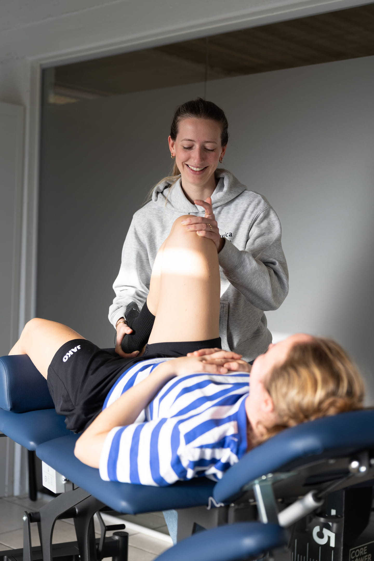 Kinesitherapeute begeleidt een patiënt bij een oefening met gewichten
